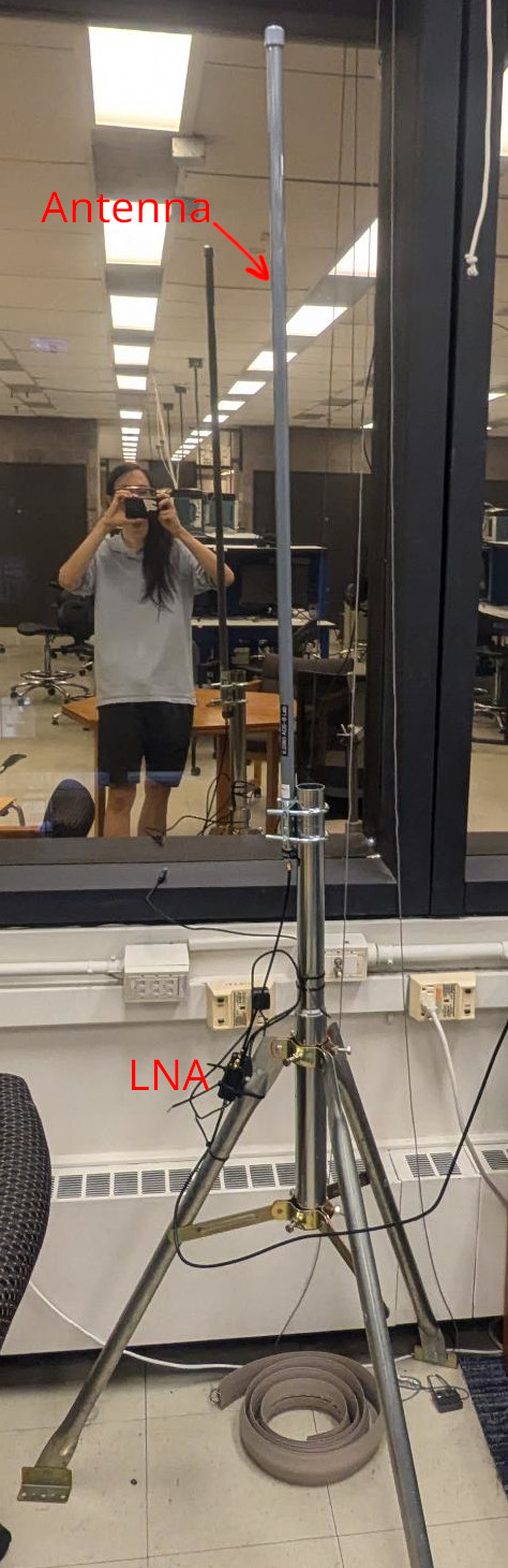 Vertical antenna mounted on tripod with LNA (black box) zip-tied to tripod leg.